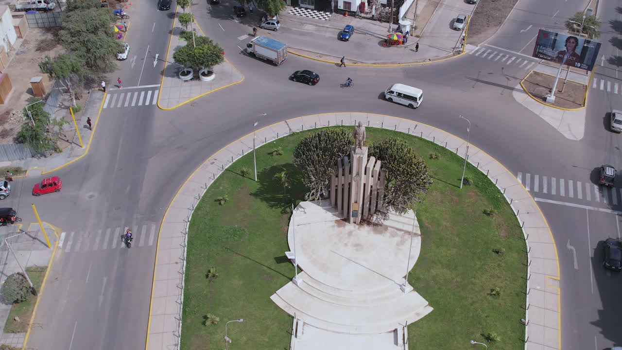 hermosa toma de drones girando sobre el famoso óvalo "ovalo quiñones" en la carretera de la ciudad de chiclayo, perú mientras los autos y la gente pasan durante el día