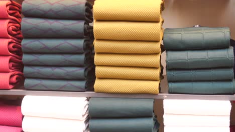 stacks of folded sweaters in a clothing store