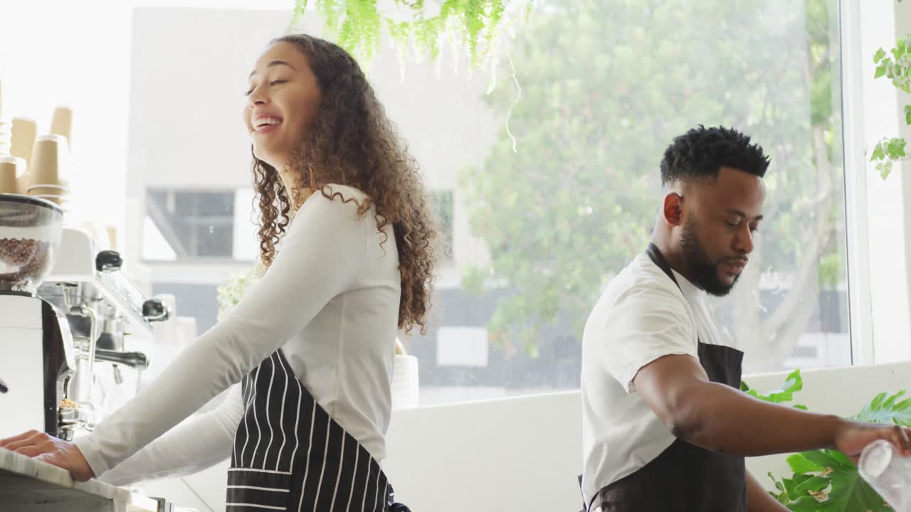 Happy african american male cafe owner and biracial female barista making coffe at cafe