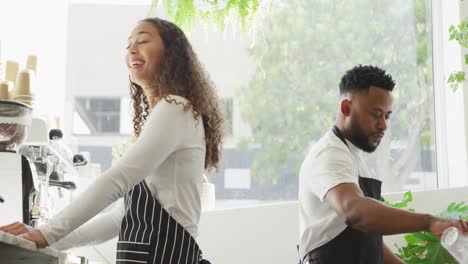 feliz dueño de un café afroamericano y barista biracial haciendo café en el café