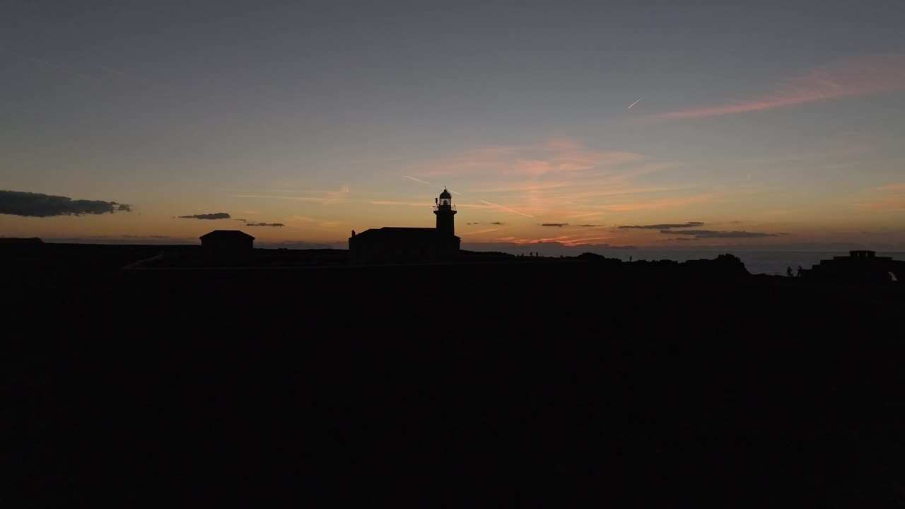 Dark silhouette shot of Punta Nati lighthouse at dusk after golden sunset in Spain