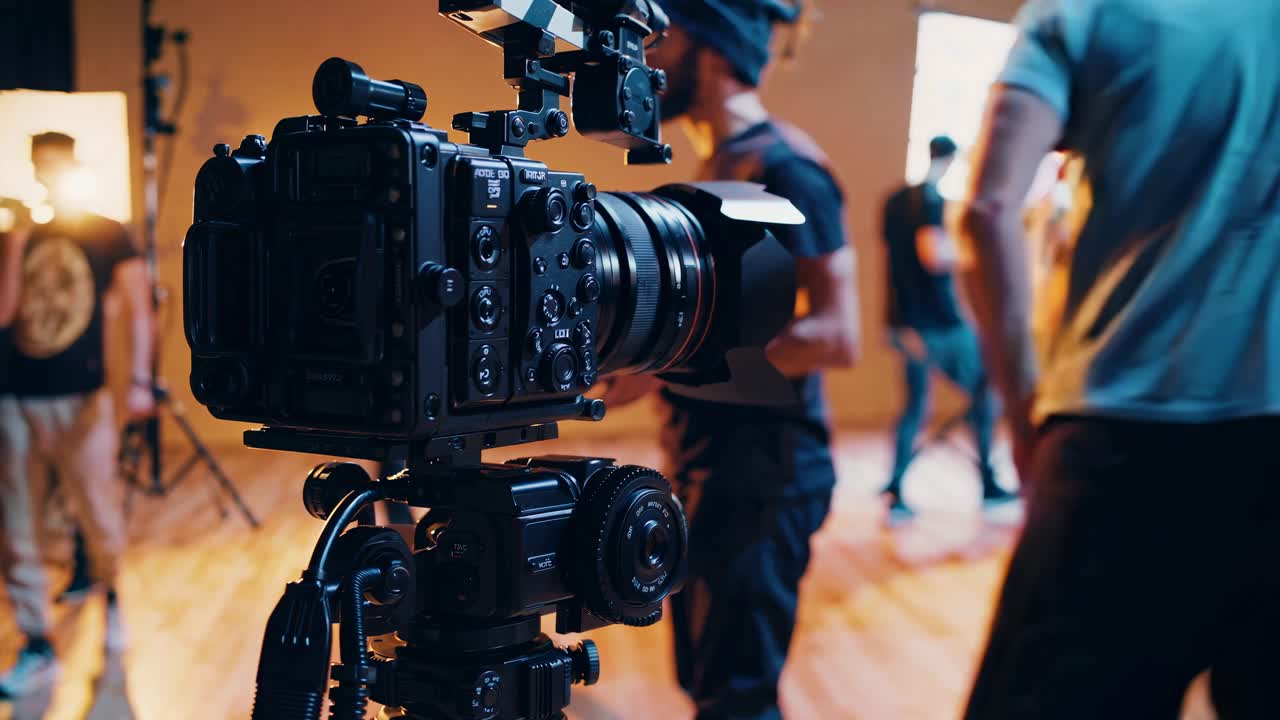 Primer plano de una cámara de vídeo profesional en un set de rodaje, capturando una vista entre bastidores con el equipo