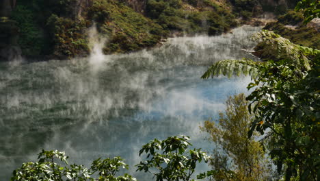 mystic toxic steam hovering over geothermal lake during sunlight in new zealand - waimangu volcanic rift valley