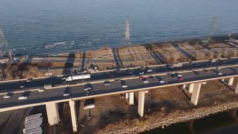 una carretera ocupada junto al lago en hamilton, ontario durante la hora dorada, tráfico ligero, vista aérea