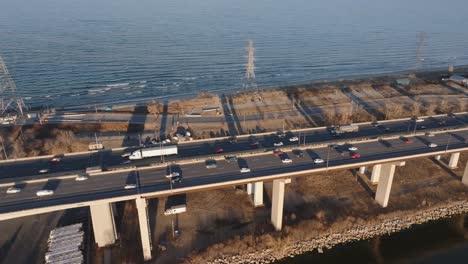 a busy highway by the lake in hamilton, ontario during golden hour, light traffic, aerial view