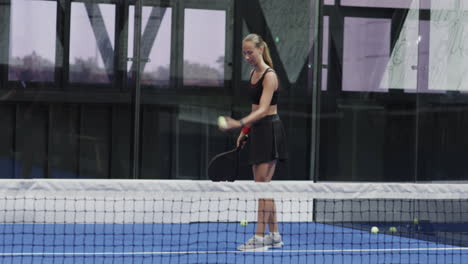 young woman playing padel tennis, swinging racket on indoor court