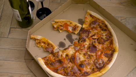 top view of a pizza in a carboard on a wooden floor