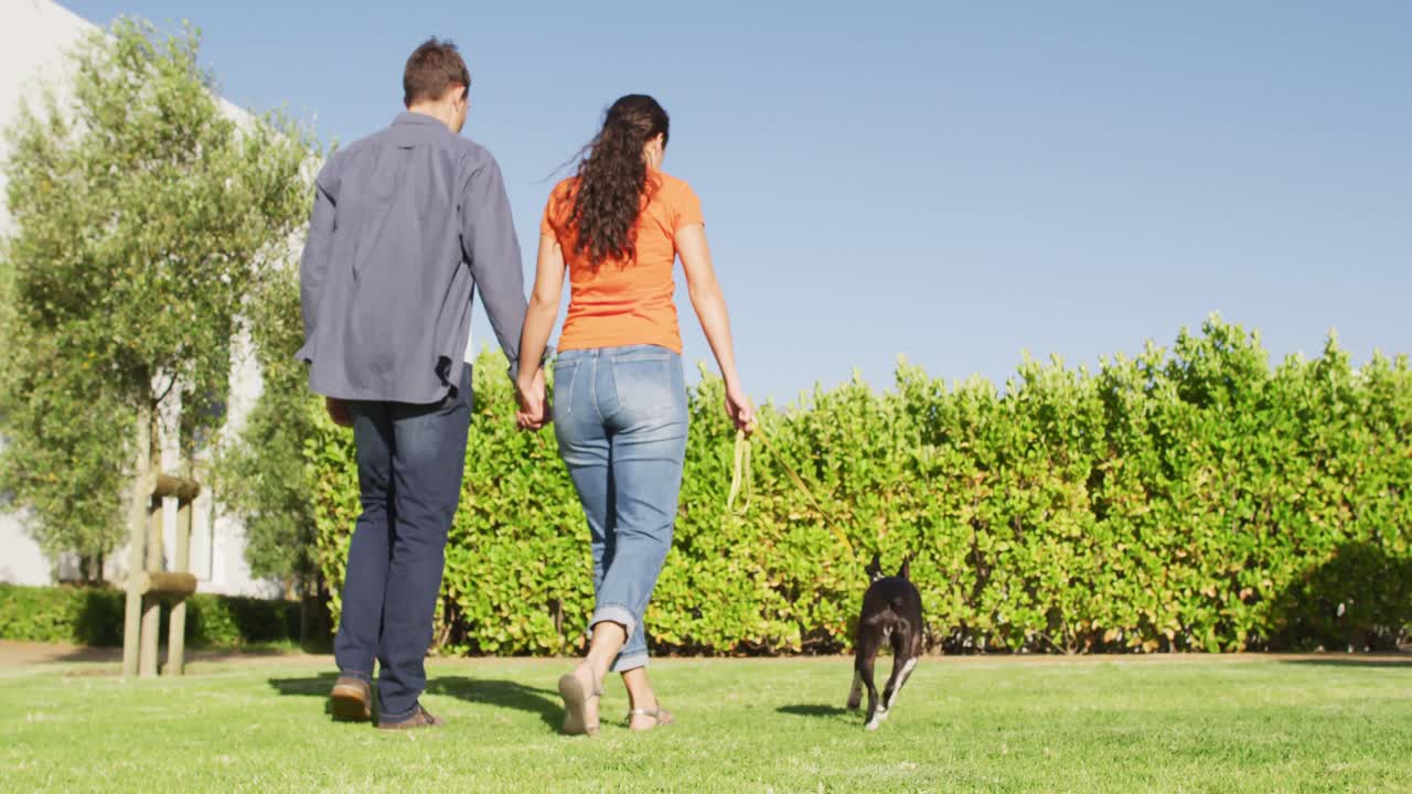 una feliz pareja caucásica está llevando a su perro a pasear