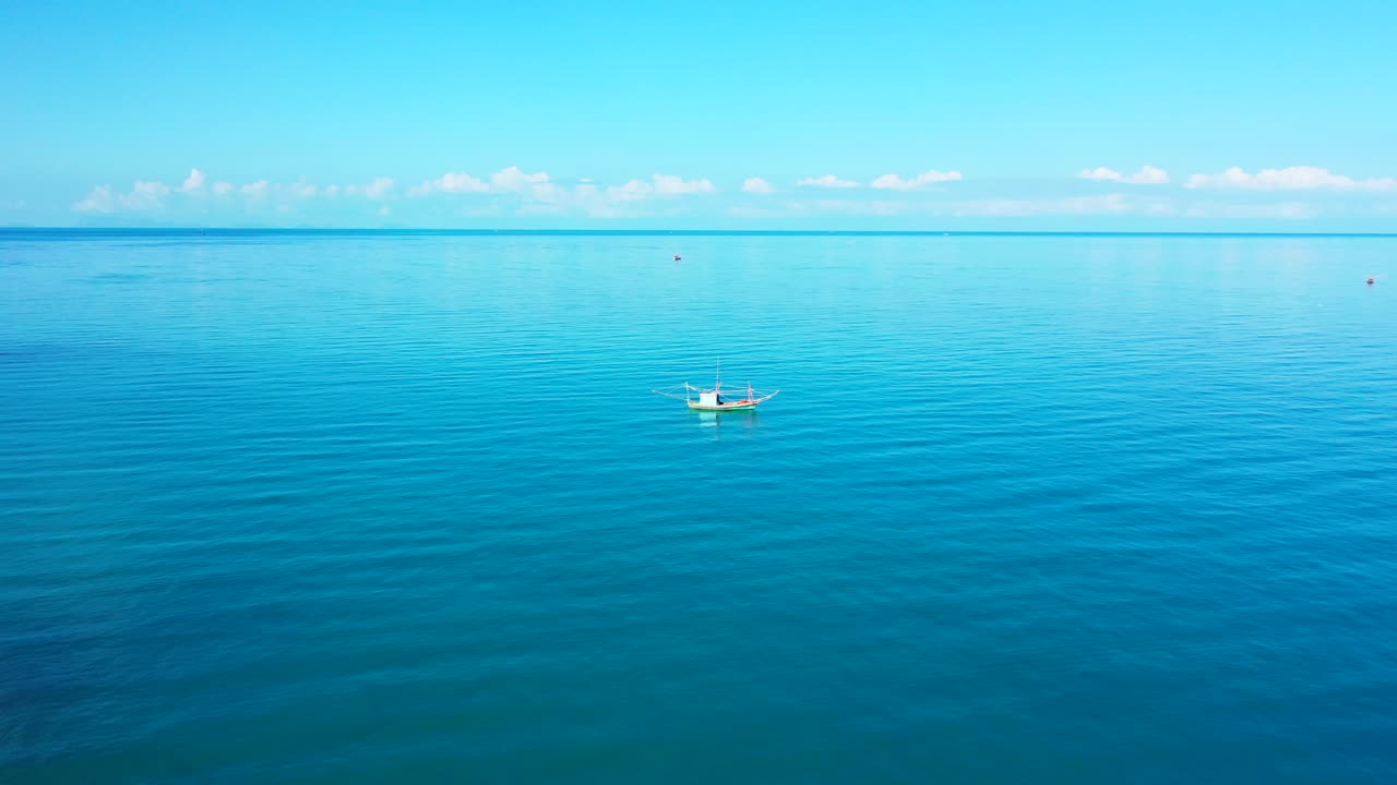캄보디아의 밝은 푸른 하늘과 함께 일출 때 열대 섬 해안 근처의 잔잔한 청록색 석호에 정박한 어선