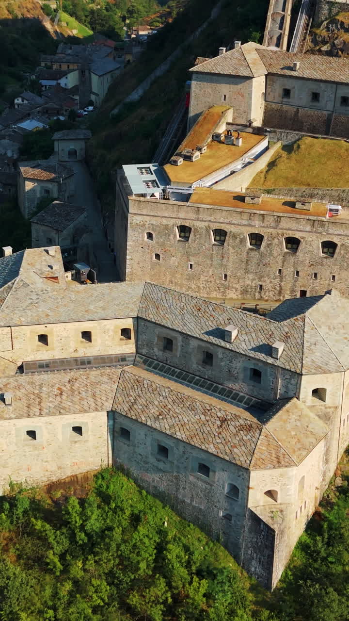 Sorvolo aereo verticale al rallentatore della storica Fortezza di Bard in pietra in Valle d'Aosta, Italia