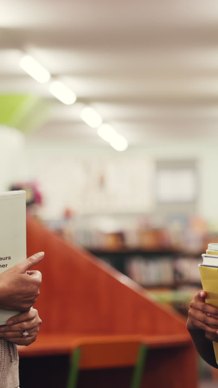 Studenti che si danno il cinque in biblioteca con dei libri