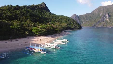 Aerial-view-Tourists-people-walking-along-palm-tree-white-sand-beach-swimming-in-crystal-clear-water