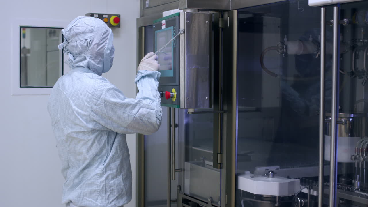 фармацевтический работник, использующий компьютерное фармацевтическое оборудование на заводе