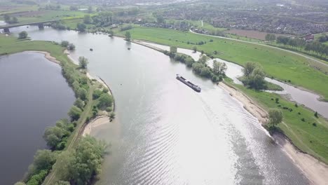 aerial footage of the container or cargo ship crossing on the river or meuse in the holland in 4k 24 fps