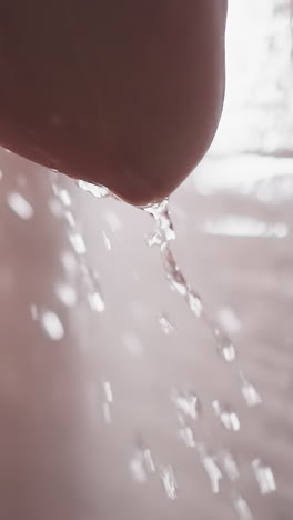 cascading water caresses skin of naked woman. woman stands under precisely temperature-controlled shower. elbow with hip of lady with running water