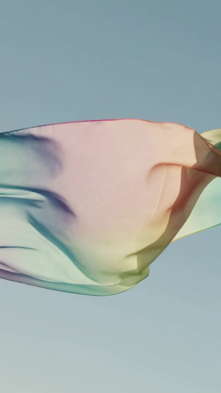 Vertical video: Light breeze lifting sheer rainbow scarf unfurling across blue sky, hand anchoring