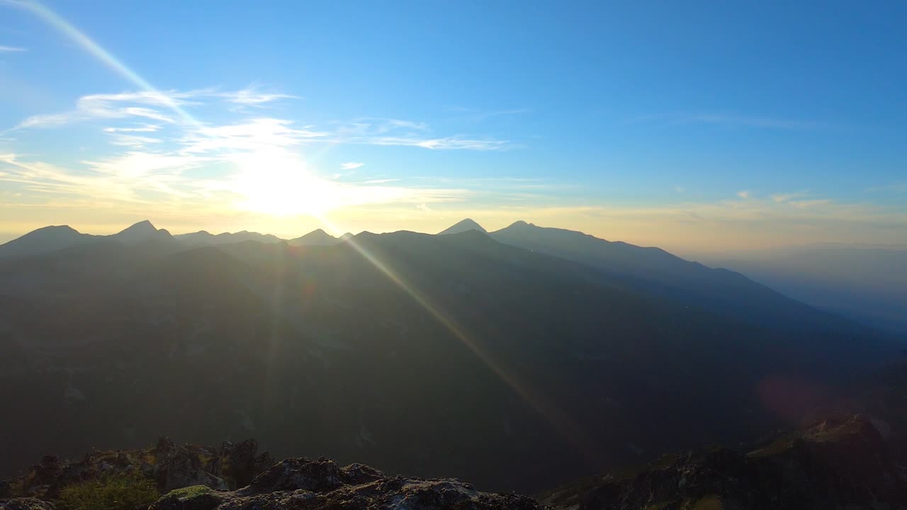 Time lapse of sunset in the mountain. The setting sun colors the horizon in yellow, orange, red. Sunbeams and clouds. Summer in Pirin.