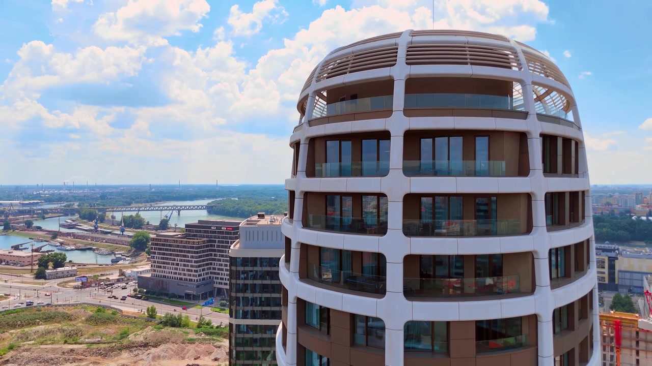 Bratislava, Slovacchia, 2 giugno 2026: Vista drone di un grattacielo ovale futuristico, Bratislava, Slovacchia. Inquadratura dal basso che mostra la facciata esterna marrone contro un cielo azzurro nuvoloso.