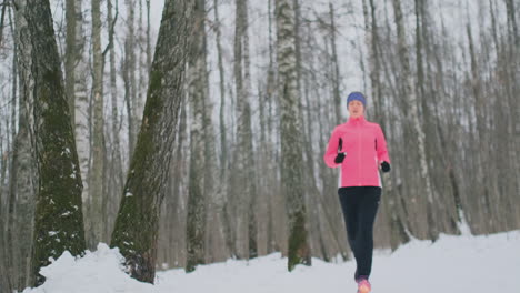 a young woman on a morning jog in the winter forest was tired and stopped to rest and ran on. he recovered his strength and overcame fatigue and continued to run. perseverance and overcoming weakness. striving forward. slow motion. healthy lifestyle