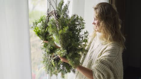 woman making christmas wreath in interior