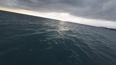 black sand beach with waves under cloudy sky, wide angle shot, genoa, italy, fpv drone shot