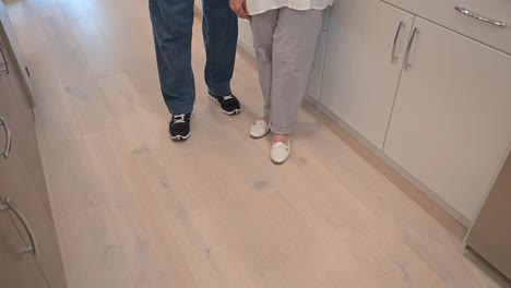 happy customers stand inside their new kitchen by the stove cooktop, and give a thumbs-up sign with their hands approving of the service