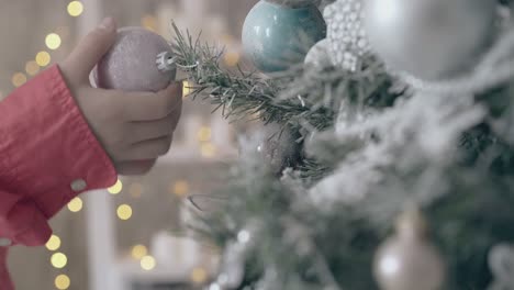 kid touches christmas decoration hanging on new year tree