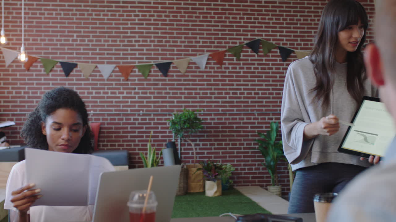 jóvenes empresarios se reúnen líder de equipo mujer presentando datos financieros utilizando una tableta mostrando a diversos colegas ideas de marketing en la presentación de la sala de juntas de la oficina