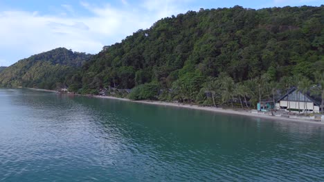 Smooth-aerial-top-view-flight-Huts-Resort-Beach-Bungalows,-Jungle-hilly-Island-Thailand-2022