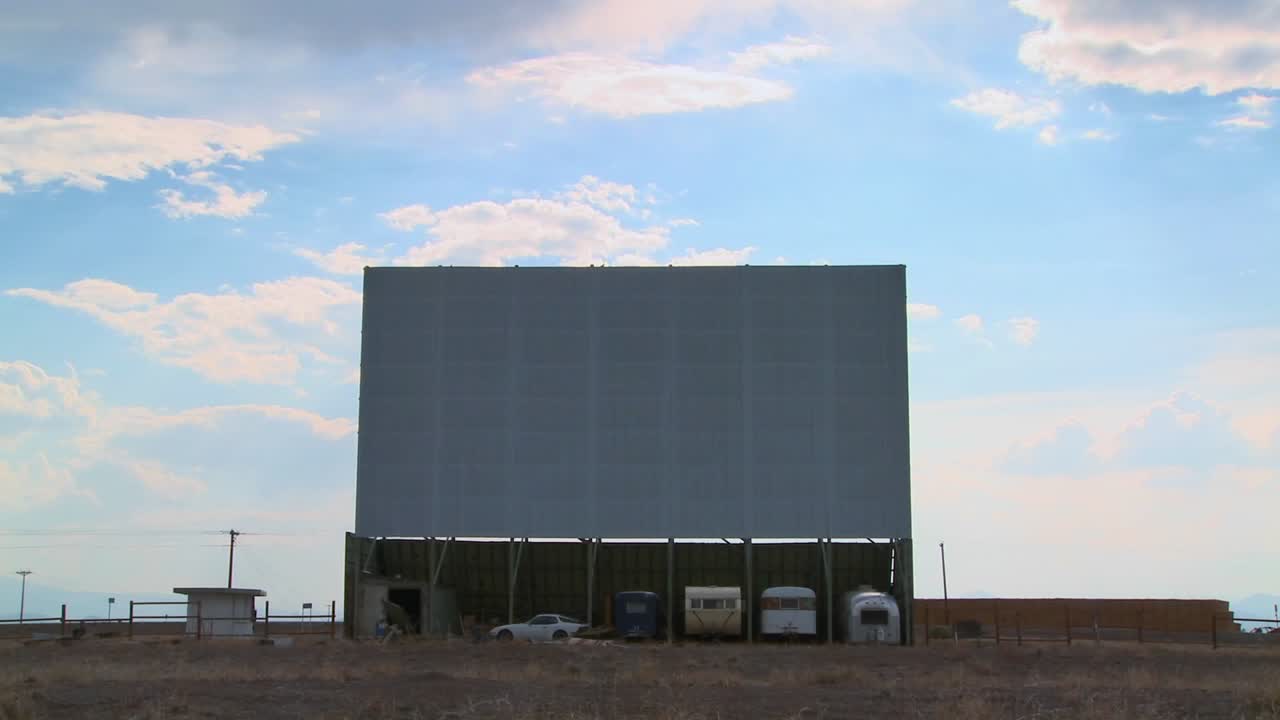 una toma de nubes pasando sobre un camino abandonado en la pantalla del cine