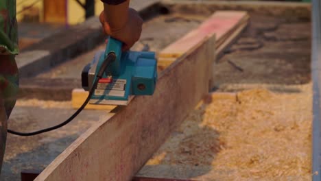 carpintero en el trabajo usando una máquina de planeado en la tabla para suavizar la tabla