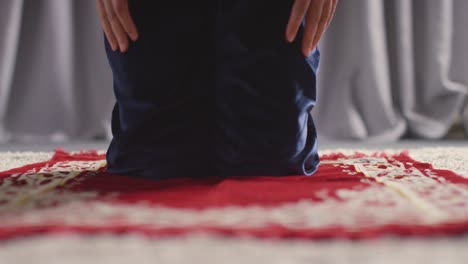 muslim woman wearing hijab at home kneeling on prayer mat and praying 4