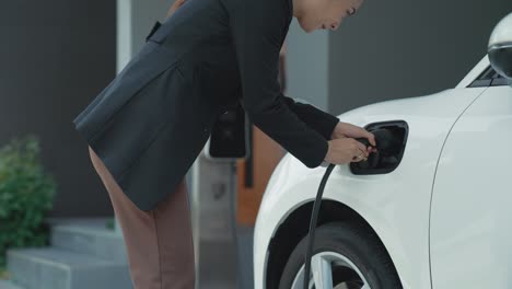 progressive woman unplugs the electric vehicle's charger at his residence.