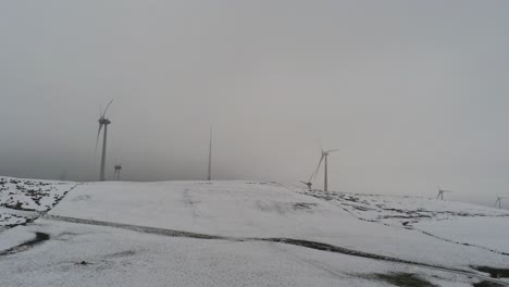 winter mountain countryside wind turbines on rural highlands aerial view cold snowy valley hillside push in