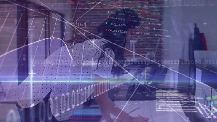 Woman leaning over desk scanning documents and annotating, analyzing stock charts overlaying desk