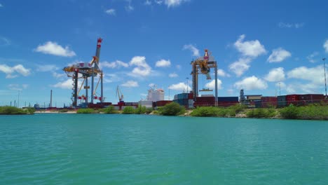 Shipping-container-port-with-two-cranes,-low-flying-aerial-dolly,-Curacao