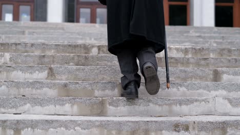 person walking up stairs with a cane