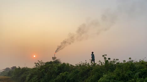 Wide-establisher-static-shot-of-man-running-in-rural-road-by-polluting-industry