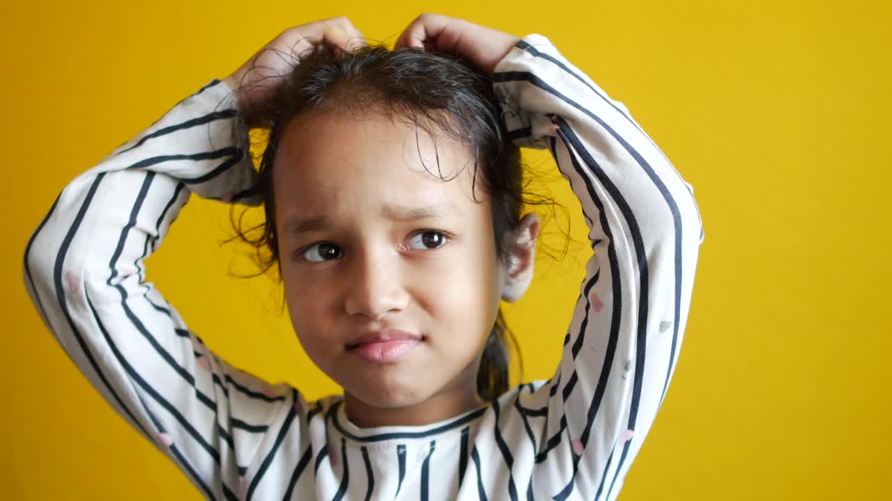 una niña triste y molesta llorando contra un fondo amarillo