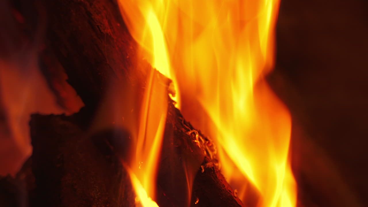 Vivid flame on wooden logs. Orange and yellow fire burning in fireplace. Bright motion of fire tongues. Macro shot.