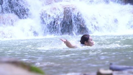 Woman Swimming in a Waterfall