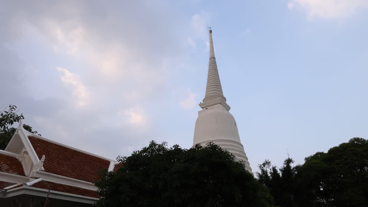A serene view of a pagoda in Bangkok, Thailand, captured at dusk with shifting clouds and soft lighting