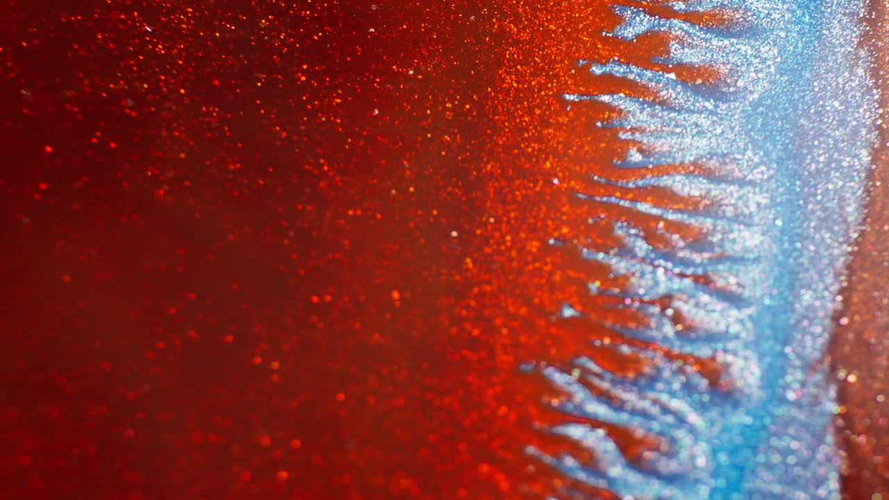 Red and blue ink bubbling, mixing with a thick liquid. Macro view