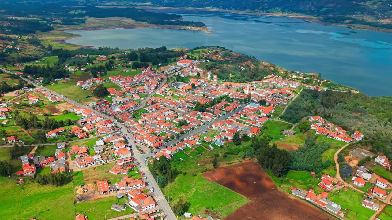 Aerial view of red-roofed Guatavita, Colombia, nestled beside the vast Tominé Reservoir lake.