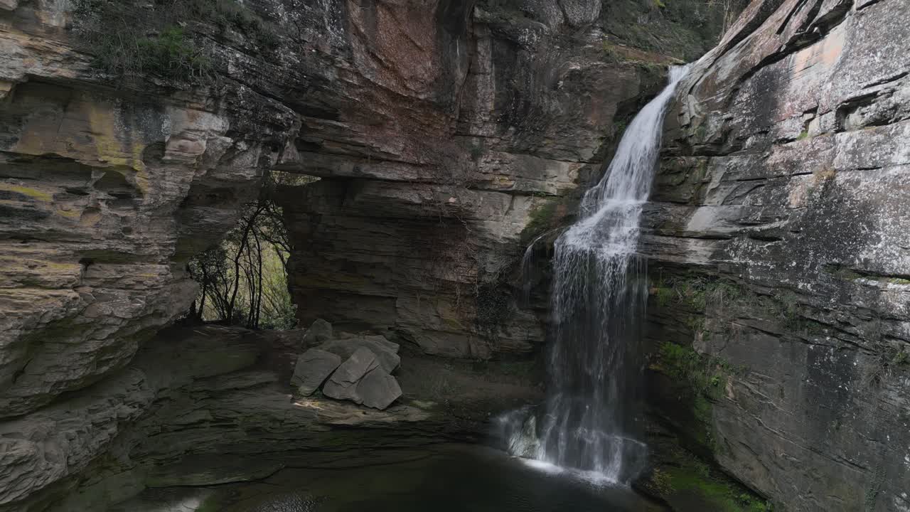 Cascading water from la foradada waterfall forming a tranquil pond within rocky gorge, highlighting pristine natural landscape near barcelona, catalonia