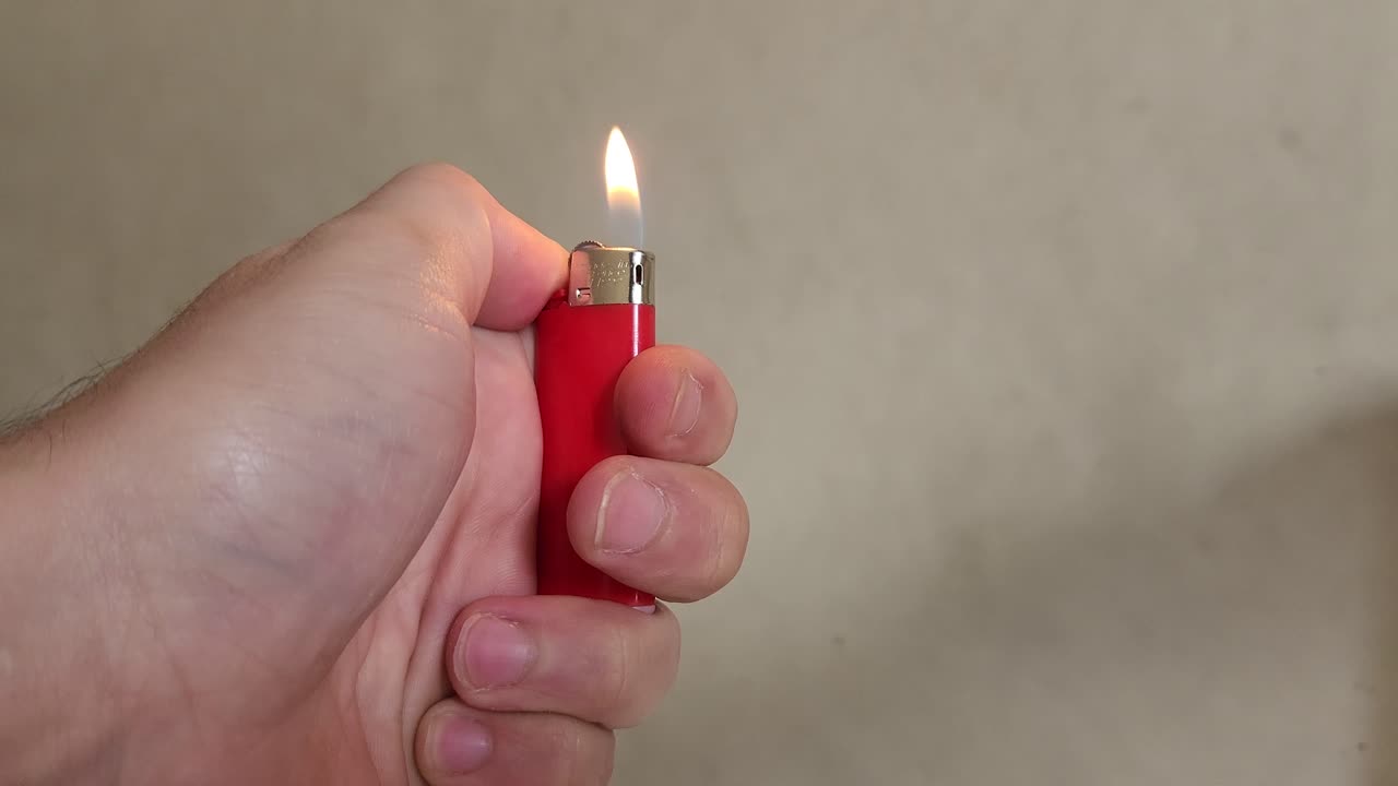 video de una mano que enciende un pequeño encendedor rojo y luego deja que la llama se apague