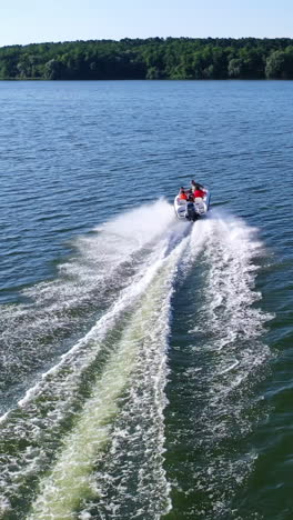 motor boat rushes along the river. beautiful view of white foam on blue river water behind the boat on nature background. aerial view. vertical video