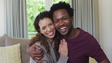 portrait of happy biracial couple looking at camera, embracing and smiling