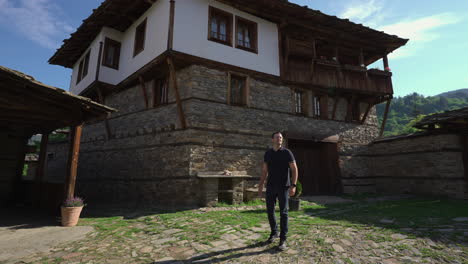 guy looking at old and traditional buildings in kovachevitsa village in garmen, bulgaria. - wide shot
