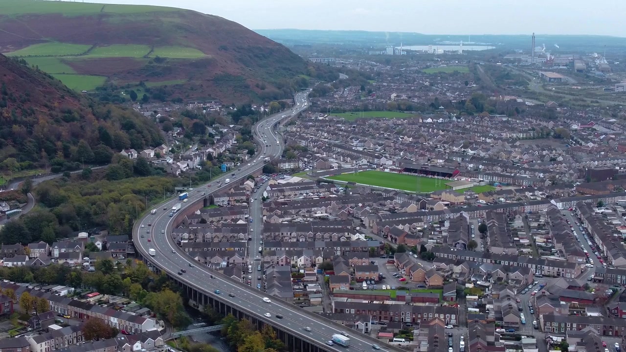 Vista del traffico sull'autostrada M4 nella città gallese di Port Talbot, con auto, furgoni e camion in movimento, insieme a case e strade 4K.